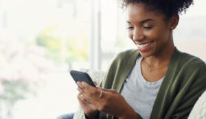 Cropped shot of an attractive young woman using her cellphone while sitting in the living room during the day