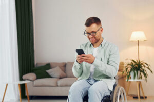 Man in wheelchair looking at his phone in his living room.