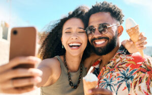 Cropped shot of an affectionate young couple taking selfies while enjoying ice cream on the beach