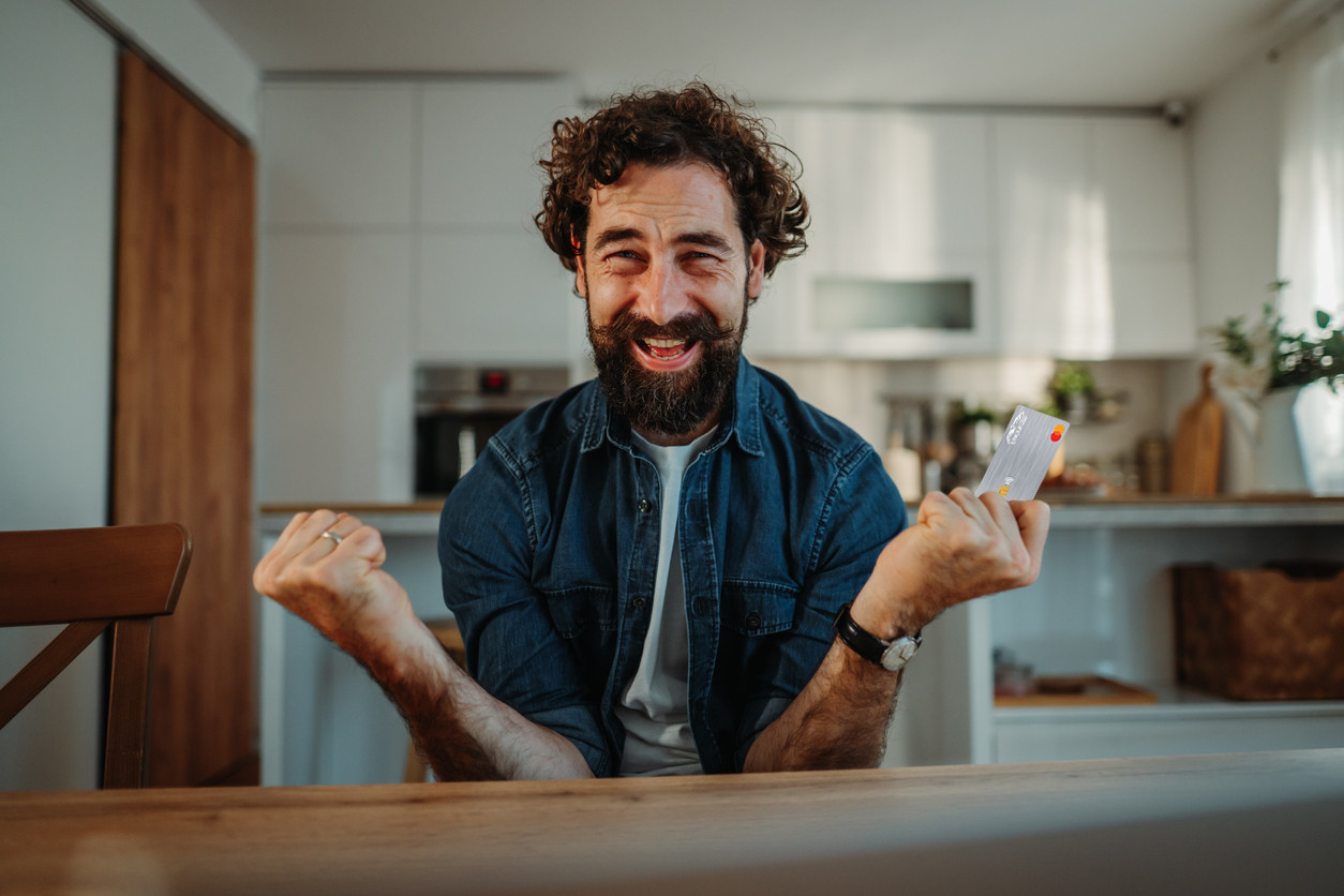 Man Holding Platinum Credit Card Excitedly In Denim Shirt