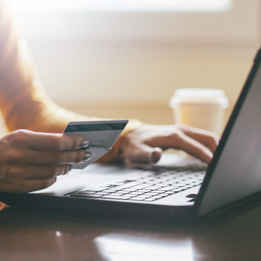 Hands holding credit card and coffee to go.