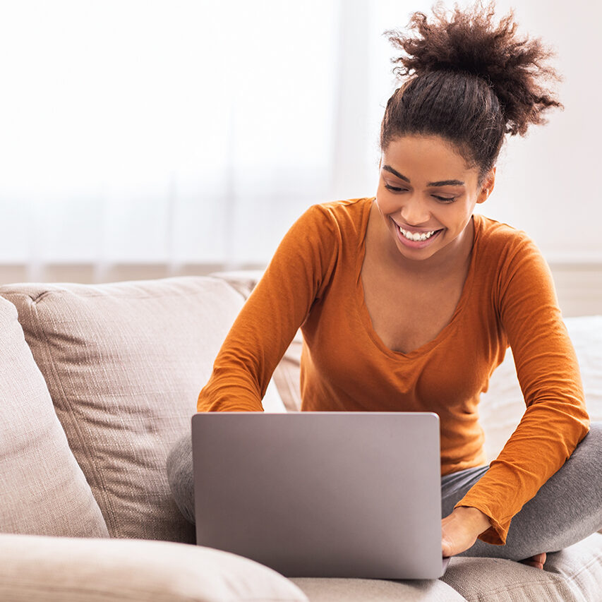 Happy Lady Using Laptop Working From Home Sitting On Sofa