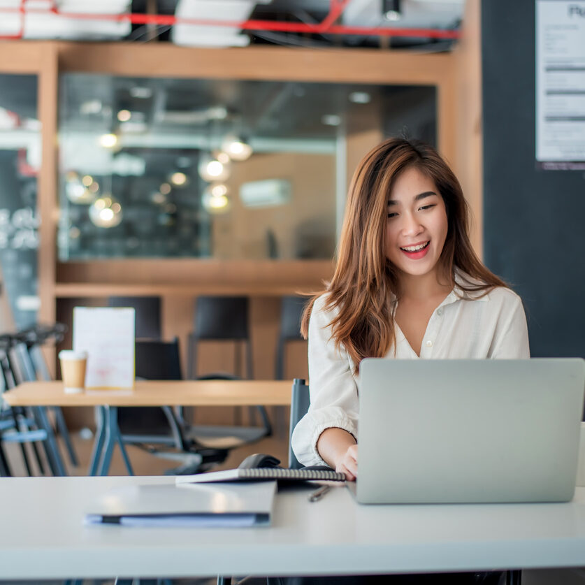 Happy young female businesswoman sitting on her workplace.