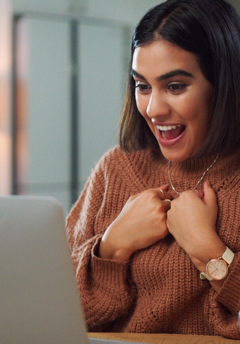 Shot of a young woman looking surprised while using a laptop at home
