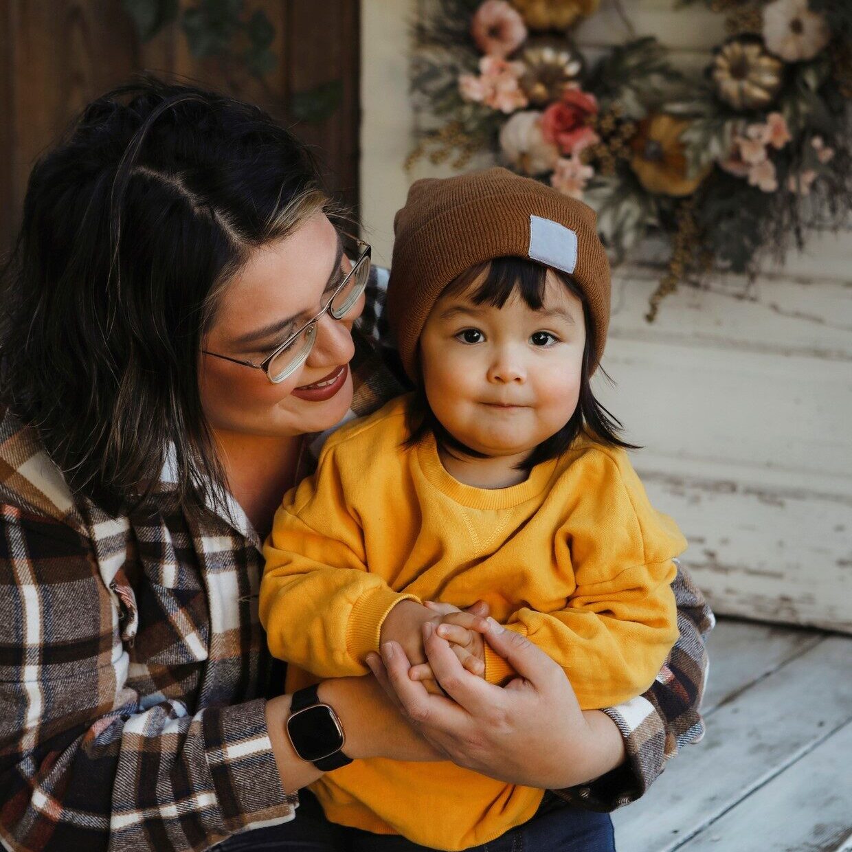 An image of a two~year~old girl and her mother, sitting on a porch.