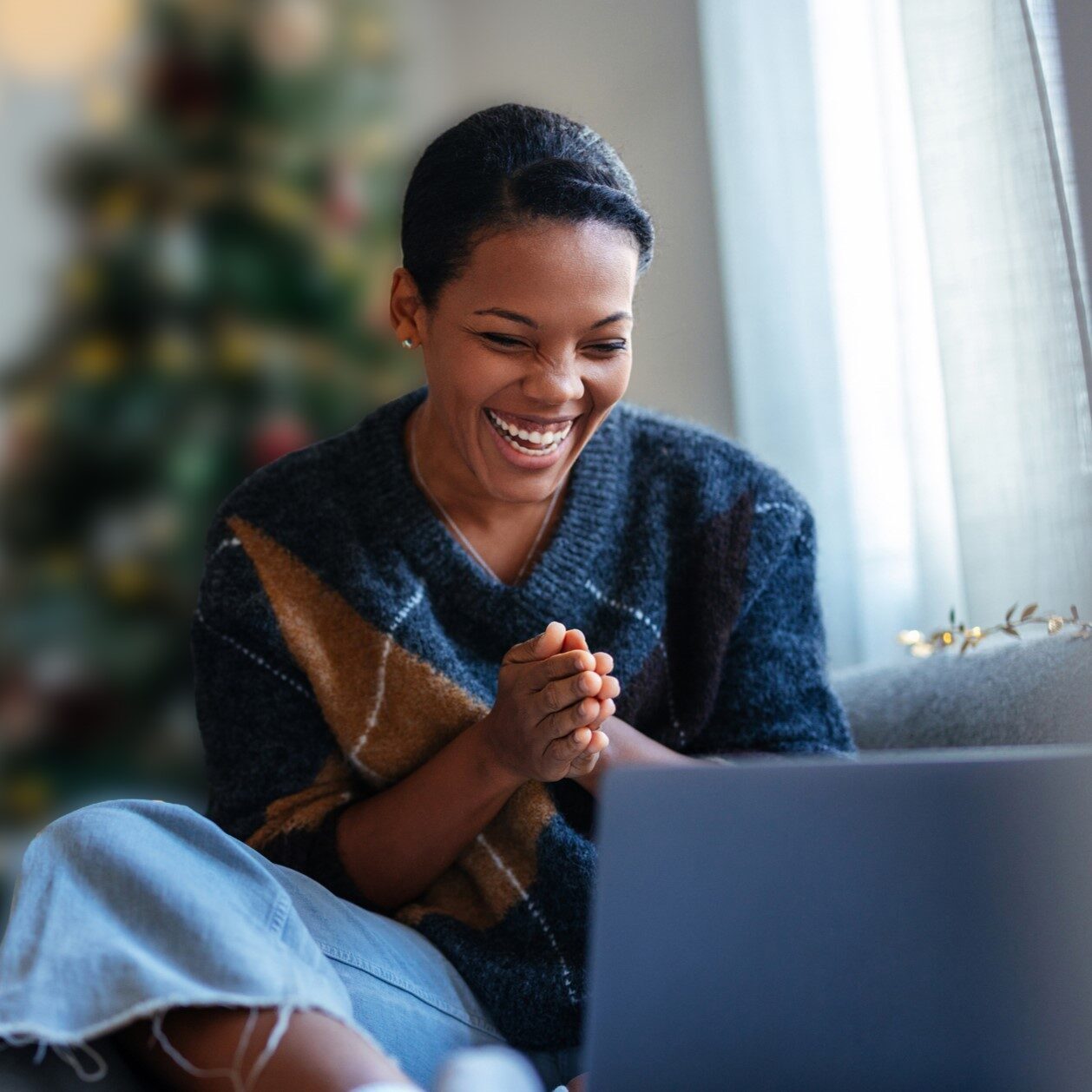 Happy woman using laptop at home on couch.